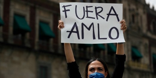 A woman holds up a sign reading “AMLO out” in Spanish during a protest in front of the National Palace, Mexico City, May 30, 2020 (AP photo by Rebecca Blackwell).