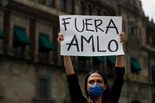 A woman holds up a sign reading “AMLO out” in Spanish during a protest in front of the National Palace, Mexico City, May 30, 2020 (AP photo by Rebecca Blackwell).
