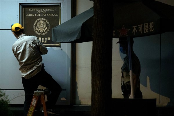 A worker tries to remove the plaque next to a Chinese paramilitary policeman from outside the United States Consulate in Chengdu, China, July 26, 2020 (AP photo by Ng Han Guan).