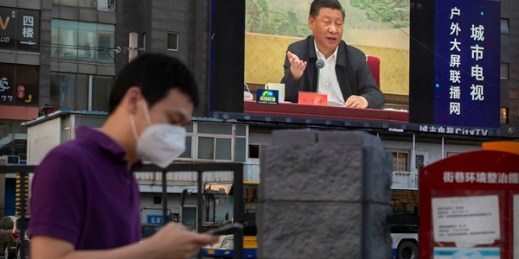 A man walks past a large video screen showing Chinese leader Xi Jinping speaking in Beijing, June 30, 2020 (AP photo by Mark Schiefelbein).