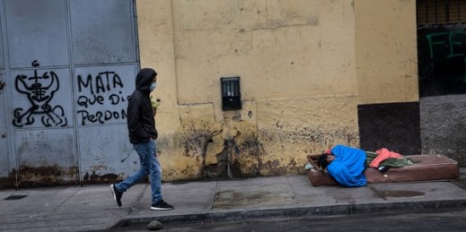 A man wearing a face mask walks near a homeless person in Lima, Peru, July 14, 2020 (AP photo by Rodrigo Abd).