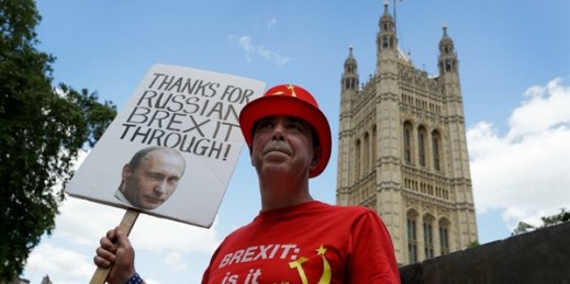 Anti-Brexit campaigner Steve Bray holds up a sign showing Vladimir Putin’s face outside Parliament in London, July 21, 2020 (AP photo by Kirsty Wigglesworth).