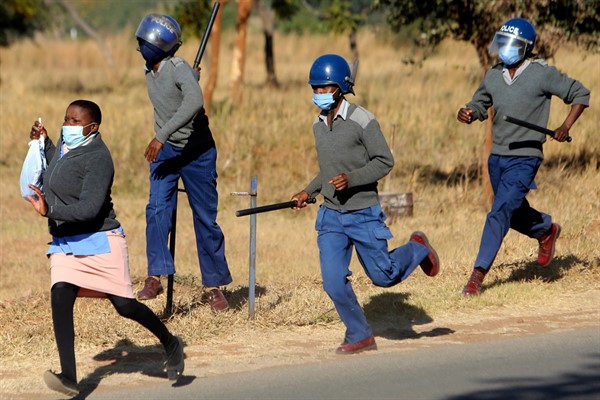 Riot police chase a nurse who was protesting at a government hospital in Harare, Zimbabwe, July, 6, 2020 (AP photo by Tsvangirayi Mukwazhi).