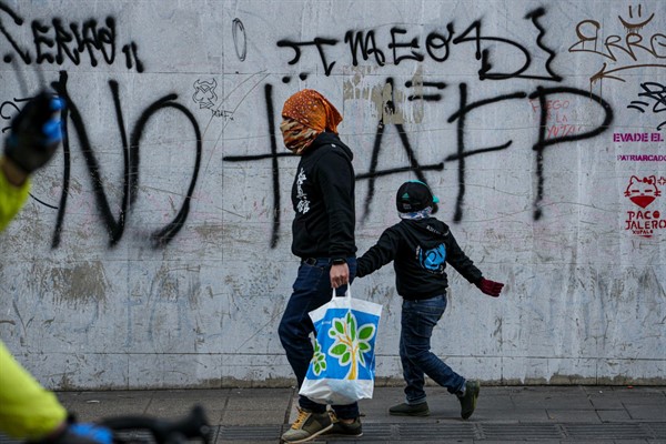 A man and a boy walk past graffiti against AFPs, Chile’s pension system, in Santiago, July 22, 2020 (AP photo by Esteban Felix).