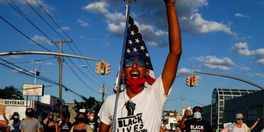 A protester carrying a U.S. flag leads a chant during a Black Lives Matter march in Valley Stream, New York, July 13, 2020 (AP photo by John Minchillo).
