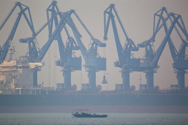A fishing boat sails near the cranes of Cao Feidian Port in Tangshan, China, Feb. 20, 2012 (AP photo by Alexander F. Yuan).