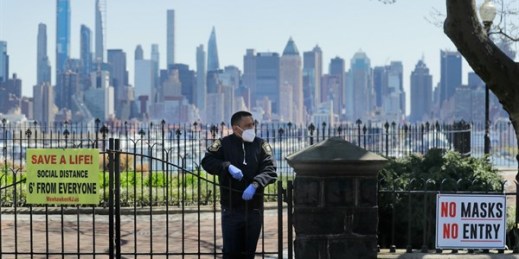 A security guard stands behind the gates of a temporarily closed park with a view of the New York City skyline, in Weehawken, N.J., April 28, 2020 (AP photo by Seth Wenig).