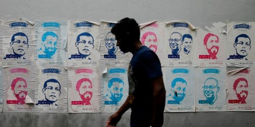 A man walks past a wall showing posters of political figures in Male, Maldives, Sept. 21, 2018 (AP photo by Eranga Jayawardena).