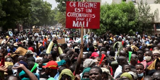 Demonstrators hold a placard in French reading, “This regime is a coronavirus for Mali,” as they protest in, Bamako, Mali, June 5, 2020 (AP photo by Baba Ahmed).