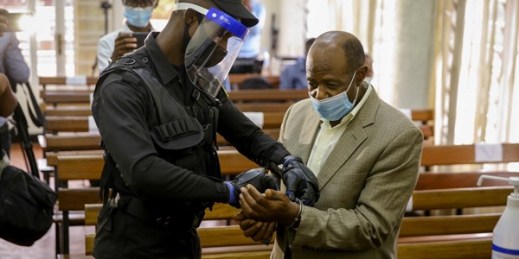 A policeman handcuffs Paul Rusesabagina, right, whose story inspired the film “Hotel Rwanda,” before leading him out of court in Kigali, Rwanda, Sept. 14, 2020 (AP photo by Muhizi Olivier).