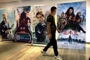 A man walks past a poster for the Disney movie “Mulan” at a movie theater in Beijing, Sept. 11, 2020 (AP photo by Mark Schiefelbein).