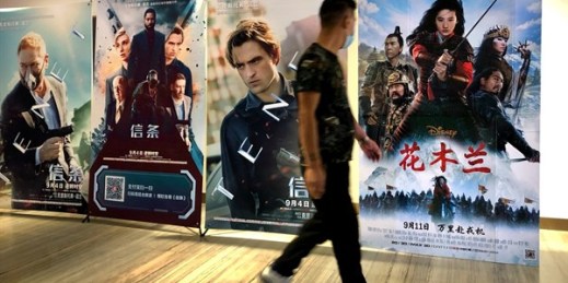 A man walks past a poster for the Disney movie “Mulan” at a movie theater in Beijing, Sept. 11, 2020 (AP photo by Mark Schiefelbein).