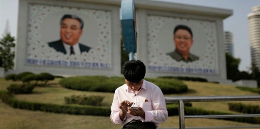 A man uses his smartphone in front of portraits of the late North Korean leaders Kim Il Sung, left, and Kim Jong Il, right, in Pyongyang, May 5, 2015 (AP photo by Wong Maye-E).