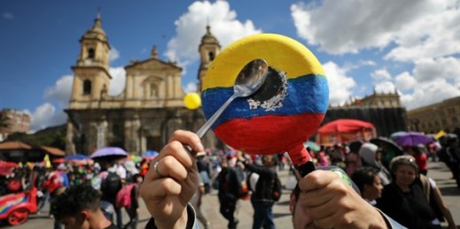 An anti-government demonstrator bangs on a pan painted with the Colombian national colors during a strike in Bogota, Colombia, Dec. 4, 2019 (AP photo by Fernando Vergara).