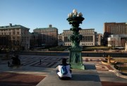 A woman sits overlooking Columbia University’s nearly empty campus, in New York, March 9, 2020 (AP photo by Mark Lennihan).