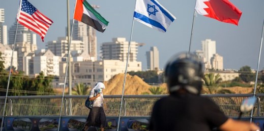 A woman walks past American, United Arab Emirates, Israeli and Bahraini flags on the Peace Bridge in Netanya, Israel, Sept. 14, 2020 (AP photo by Ariel Schalit).