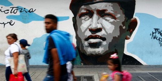 Pedestrians walk past a mural depicting the late Venezuelan President Hugo Chavez, in Caracas, Venezuela, Aug. 6, 2019 (AP photo by Leonardo Fernandez).