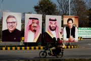 A motorcycle rides past portraits of Pakistani and Saudi leaders on display in Islamabad, Pakistan, Feb. 15, 2019 (AP photo by B.K. Bangash). Saudi-Pakistan relations, historically close, have recently hit a snag.