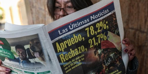 A woman reads a newspaper showing the results of the previous day’s referendum in favor of rewriting the nation’s constitution, in Santiago, Chile, Oct. 26, 2020 (AP photo by Esteban Felix).