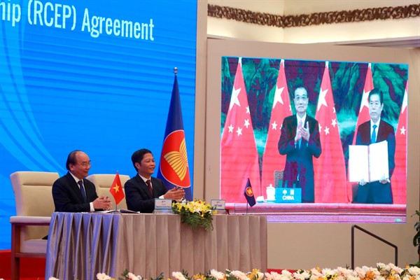 Vietnamese Prime Minister Nguyen Xuan Phuc, left, and Minister of Trade Tran Tuan Anh, right, next to a screen showing Chinese Premier Li Keqiang and Minister of Commerce Zhong Shan, during the RCEP signing ceremony, Hanoi, Vietnam (AP photo by Hau Dinh).