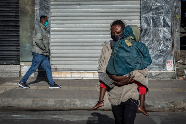 A man carries a child across a street in Addis Ababa, Ethiopia, Nov. 13, 2020 (AP photo by Mulugeta Ayene).