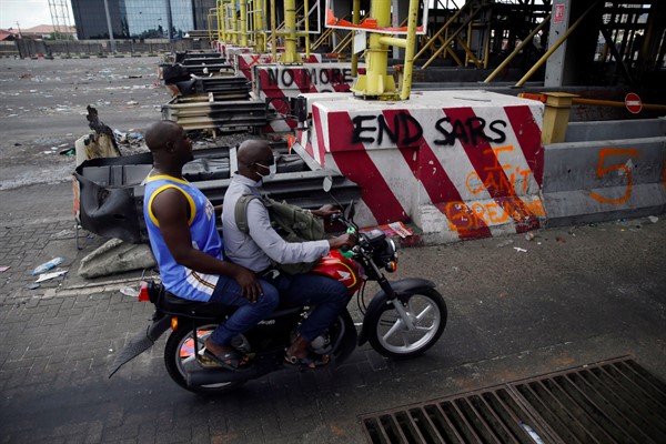 People drive past burnt toll gates showing anti-police slogans, in Lagos, Nigeria, Oct. 23, 2020 (AP photo by Sunday Alamba).