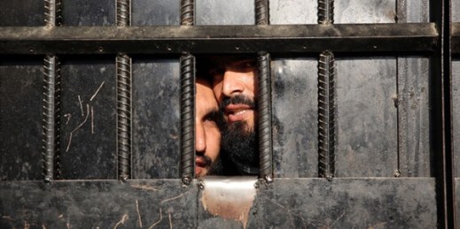 Taliban prisoners peer through a door after an ISIS-claimed attack on a prison in Jalalabad, Afghanistan, Aug. 3, 2020 (AP photo by Rahmat Gul).