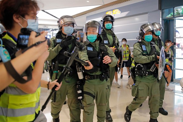 A riot police officer hits a journalist’s microphone during a protest at a shopping mall in Hong Kong, July 21, 2020 (AP photo by Kin Cheung).