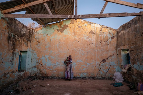 A woman holds her child inside a temporary shelter at Umm Rakouba refugee camp after fleeing the conflict in Ethiopia’s Tigray region, in Qadarif, eastern Sudan, Dec. 7, 2020 (AP photo by Nariman El-Mofty).