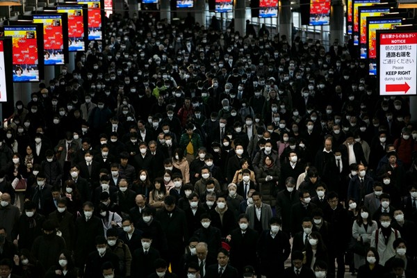 A large crowd wearing masks commutes through Shinagawa Station in Tokyo, Japan, Mar. 3, 2020 (AP photo by Jae C. Hong).