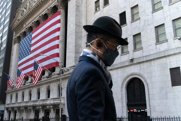 A man passes the New York Stock Exchange, Nov. 16, 2020 (AP photo by Mark Lennihan).