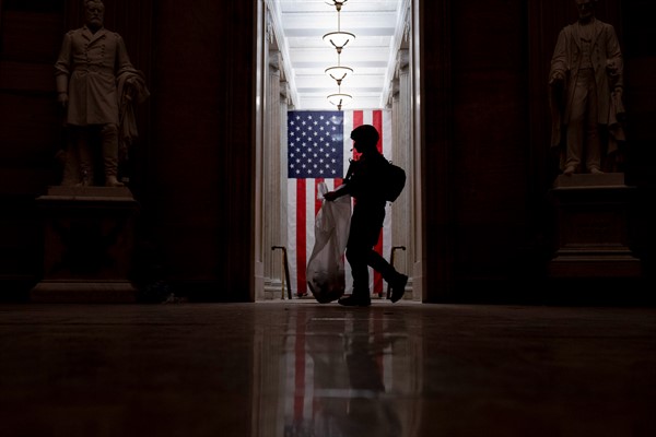 A police officer cleans up debris strewn across the floor of the Capitol Rotunda, in Washington, during the early morning hours of Jan. 7, 2021 (AP photo by Andrew Harnik).