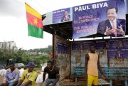 People sit under campaign election posters of President Paul Biya, in Yaounde, Cameroon, Oct. 5. 2018 (AP photo by Sunday Alamba).