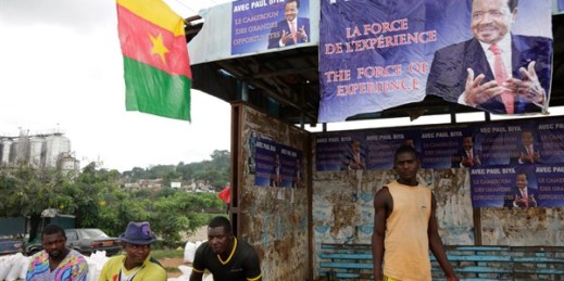 People sit under campaign election posters of President Paul Biya, in Yaounde, Cameroon, Oct. 5. 2018 (AP photo by Sunday Alamba).