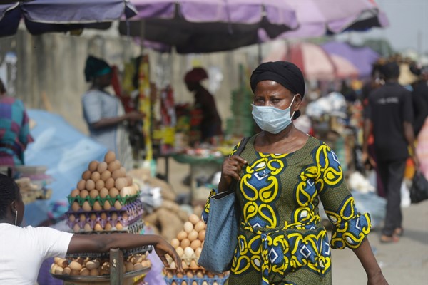 A woman walks by a market in Lagos, Nigeria, Dec. 31, 2020 (AP photo by Sunday Alamba).