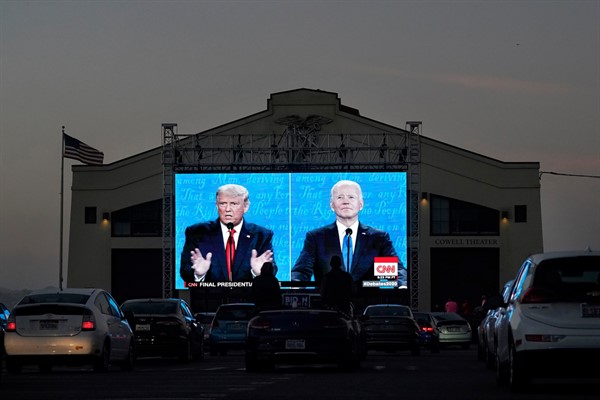 People watch then-President Donald Trump, on left of video screen, and Democratic presidential candidate Joe Biden speak during a presidential debate watch party, San Francisco, Oct. 22, 2020 (AP photo by Jeff Chiu).