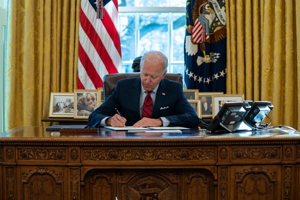President Joe Biden signs a series of executive orders in the Oval Office of the White House, Washington, Jan. 28, 2021 (AP photo by Evan Vucci).