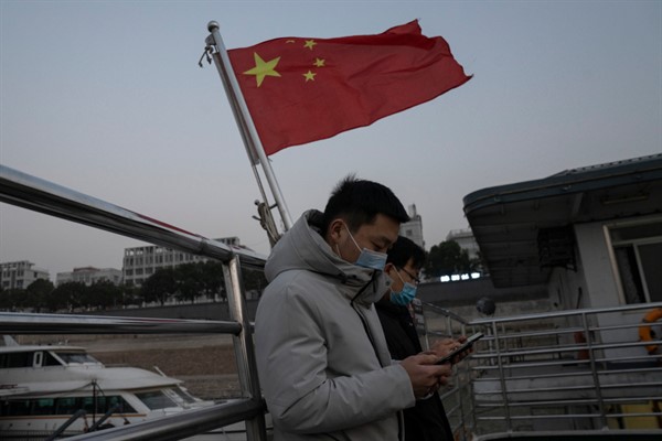 Residents taking the ferry stand near a Chinese national flag in Wuhan, China, Jan. 15, 2021 (AP photo by Ng Han Guan).