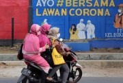Women ride past a coronavirus-themed mural reading “Come on together fight the coronavirus,” in Jakarta, Indonesia, Sep. 10, 2020 (AP photo by Tatan Syuflana).