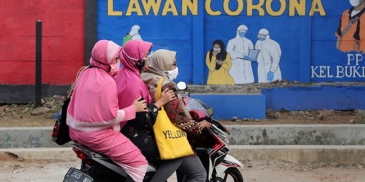 Women ride past a coronavirus-themed mural reading “Come on together fight the coronavirus,” in Jakarta, Indonesia, Sep. 10, 2020 (AP photo by Tatan Syuflana).