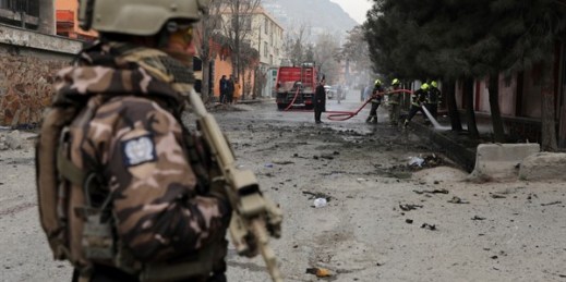 A soldier stands guard as firefighters work at the site of a bomb attack in Kabul, Afghanistan, Feb. 20, 2021 (AP photo by Rahmat Gul).