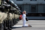 A woman kneels in front of a riot police line as they block a rally of Belarusian opposition supporters in the center of Minsk, Belarus, Aug. 30, 2020 (AP photo).