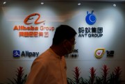 An employee walks past the logos of Ant Group and Alibaba Group at the Ant Group office in Hong Kong, Oct. 23, 2020 (AP photo by Kin Cheung).