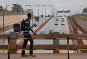 A pedestrian crosses a bridge over a new 30-mile highway that was built by three Chinese companies and financed by the African Development Bank and the Exim Bank of China, leading north of Nairobi, Kenya, Oct. 10, 2012 (AP photo by Ben Curtis).