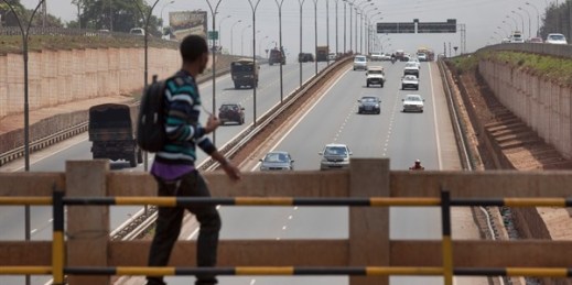 A pedestrian crosses a bridge over a new 30-mile highway that was built by three Chinese companies and financed by the African Development Bank and the Exim Bank of China, leading north of Nairobi, Kenya, Oct. 10, 2012 (AP photo by Ben Curtis).