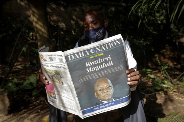 A man reads a copy of the Daily Nation morning newspaper reporting the death of neighboring Tanzania’s president, John Magufuli, on a street in Nairobi, Kenya, March 18, 2021 (AP photo by Khalil Senosi).