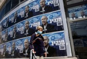 A woman passes Likud party campaign posters for Prime Minister Benjamin Netanyahu in the city of Sderot, Israel, March 19, 2021 (AP photo by Tsafrir Abayov).