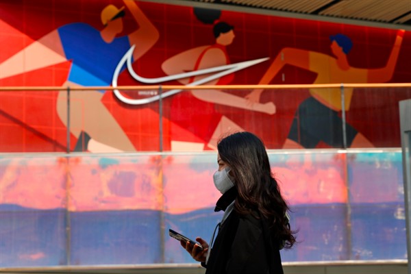 A woman walks past a Nike store in Beijing, March 25, 2021 (AP photo by Ng Han Guan).