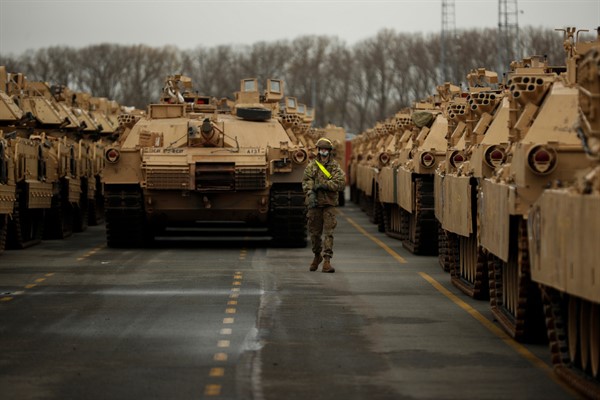 A U.S. soldier walks past parked armored vehicles and tanks of the 1st Armored Brigade Combat Team and 1st Calvary Division, based out of Fort Hood, Texas, as they are unloaded in Antwerp, Belgium, Nov. 16, 2020 (AP photo by Francisco Seco).