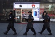 Security guards march past a shop selling Apple and Huawei phones in Beijing, China, March 6, 2019 (AP photo by Ng Han Guan).